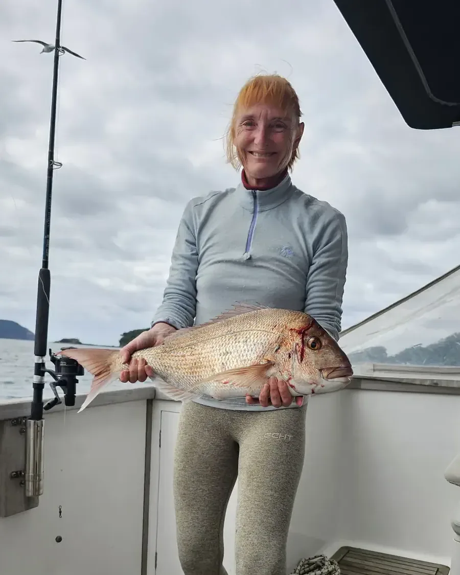 Sandra Tanner on the launch, holding a snapper she has just landed